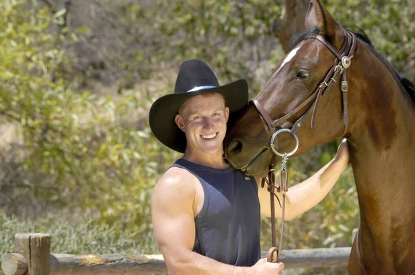 一个英俊的牛仔和他的马在一个有趣的摄影中合影 — 图库照片
