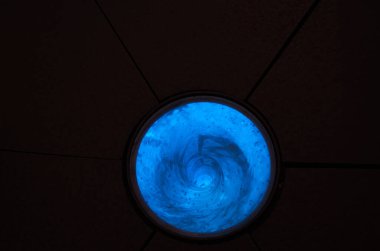 a glass of water with a blue light and a black background.