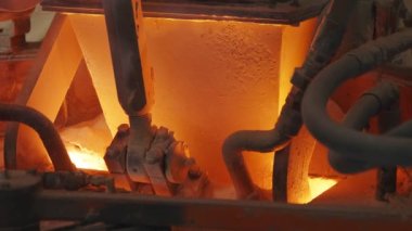Cam üretim fabrikasında eriyen bir fırına ham maddeler dökülüyor.