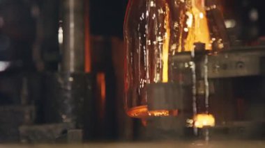Cam şişe üretimi. Bir üretim tesisinde kırmızı sıcak cam şişeler