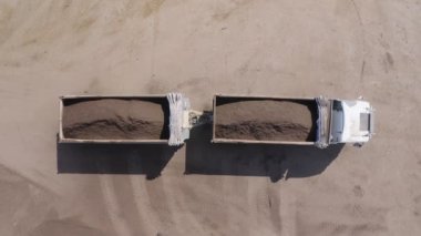 Endüstriyel gübre üretim alanı. Gübre yığınlarını ve traktörleri gösteren makineler gübre yüklüyor