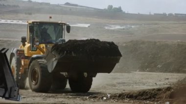 İndüksiyon gübre üretim alanı. Gübre yığınlarını ve traktörleri gösteren makineler gübre yüklüyor