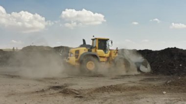 İndüksiyon gübre üretim alanı. Gübre yığınlarını ve traktörleri gösteren makineler gübre yüklüyor