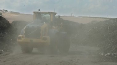İndüksiyon gübre üretim alanı. Gübre yığınlarını ve traktörleri gösteren makineler gübre yüklüyor