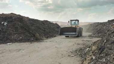 İndüksiyon gübre üretim alanı. Gübre yığınlarını ve traktörleri gösteren makineler gübre yüklüyor