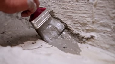 Close up of brush applying mortar for waterproofing the bathroom floor