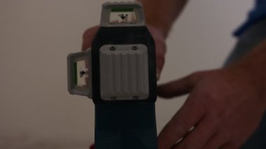 Close up of construction worker using a laser level to measure and mark