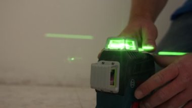Close up of construction worker using a laser level to measure and mark