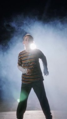 Dansçı yavaş çekimde hip hop dansı yapıyor, ışık ve duman arka planında.