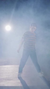 Dansçı yavaş çekimde hip hop dansı yapıyor, ışık ve duman arka planında.
