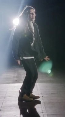 Dansçı yavaş çekimde hip hop dansı yapıyor, ışık ve duman arka planında.