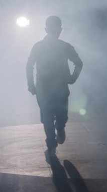 Dansçı yavaş çekimde hip hop dansı yapıyor, ışık ve duman arka planında.
