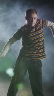 Dansçı yavaş çekimde hip hop dansı yapıyor, ışık ve duman arka planında.