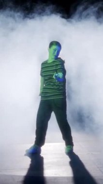 Dansçı yavaş çekimde hip hop dansı yapıyor, ışık ve duman arka planında.