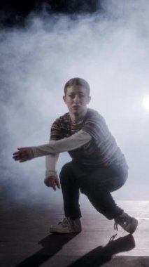 Dansçı yavaş çekimde hip hop dansı yapıyor, ışık ve duman arka planında.