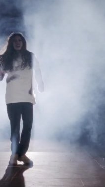 Dansçı yavaş çekimde hip hop dansı yapıyor, ışık ve duman arka planında.