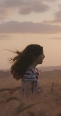 Gün batımı sırasında altın bir alanda genç kız