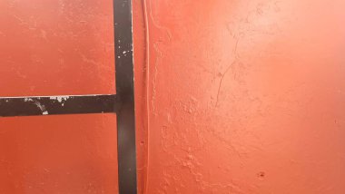 Siyah çerçeveli kırmızı bir duvar ve beyaz H harfi.