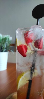 İçinde siyah pipet olan uzun bir bardak meyve kokteyli. Cam ahşap bir masanın üzerinde.