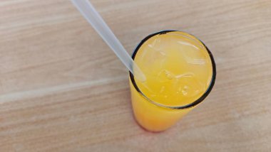 İçinde pipet olan bir bardak portakal suyu. Bardağın yarısı dolu ve pipet üstten sarkıyor.