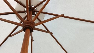 Beyaz gölgelikli ahşap bir şemsiye. Şemsiye ahşaptır ve kahverengi bir sapı vardır.