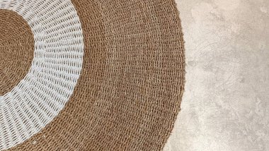 Ortasında beyaz şerit olan kahverengi ve beyaz bir halı. Halı gri bir zemine yerleştirildi.