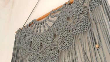 Düğümlerden oluşan bir deseni ve ahşap çerçevesi olan gri ve beyaz bir duvar.