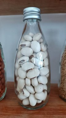 Beyaz fasulyelerle dolu cam bir şişe.