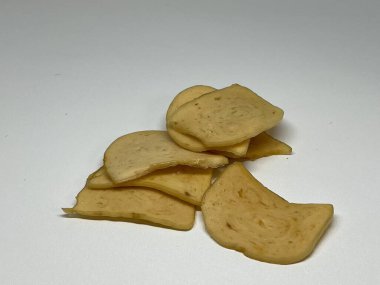 Beyaz bir yüzeye dizilmiş küçük sarı peynir dilimleri..