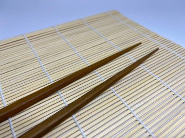 Bir çift ahşap çubuk bambu hasırın üzerinde dinleniyor. Genellikle akşam yemeği için kullanılır..