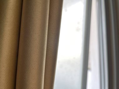 Yumuşak bej perdeler bir pencereyi kısmen bulanık v ile kaplıyor