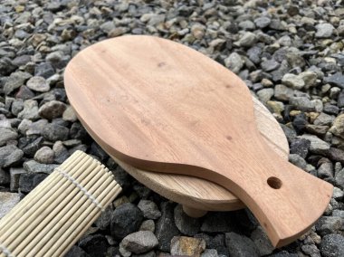 Tahta bir kürek ve çakılların üzerinde duran bambu bir paspas..