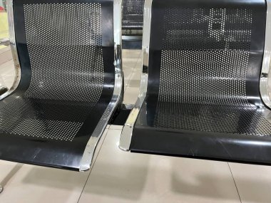 Bekleme salonunda delinmiş koltuklu iki modern metal sandalye..