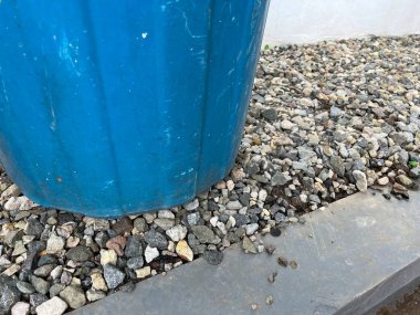 Mavi bir saksı çakılların üzerinde oturur, bahçeyi ya da dışarıyı aydınlatır. 