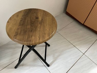 Minimumda siyah metal çerçeve olan yuvarlak tahta bir tabure.