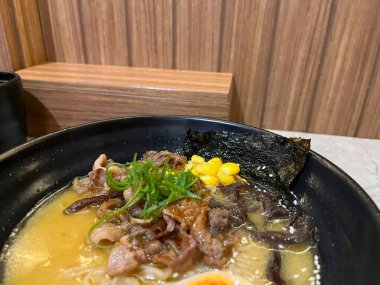 İçinde et, sebze, yosun ve yumurta bulunan bir kase ramen.,