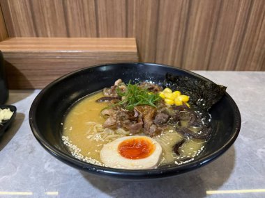 İçinde çorba, erişte, et, yumurta, mısır ve et olan bir kase ramen.