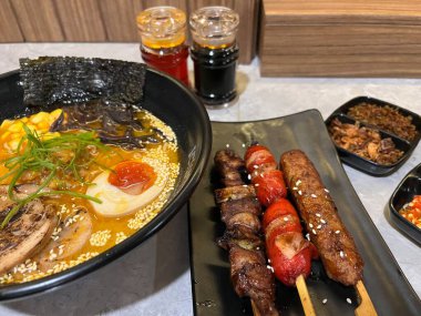 İçinde ramen, şiş et ve sos bulunan lezzetli bir yemek. 