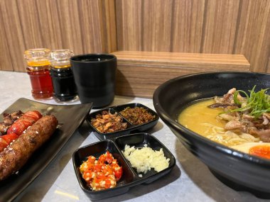 Yanında meze ve içeceklerle bir kase ramen.