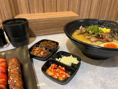 Lezzetli bir kase ramen, yanında da meze ve içecek. 