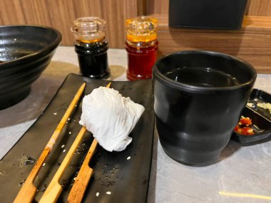 Yemek çubukları, soslar ve bir fincandan oluşan bir yemek takımı.