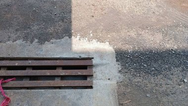 Metal ızgara ve çakıllı beton bir yüzey, dokular arasındaki geçişi gösteriyor..