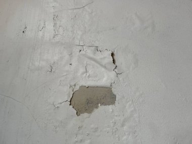 Bir iç duvar, beyaz boyanın soyulduğunu gösteriyor. Altındaki yüzeyi ortaya çıkaran büyük bir çatlak. Bu da ev geliştirme projesi için..