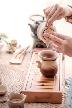 Kadın masaya kil bardaktan çay dolduruyor.