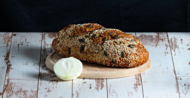 Tahtada susam, kabak tohumu ve soğan olan somun ekmeğinin üst görüntüsü.