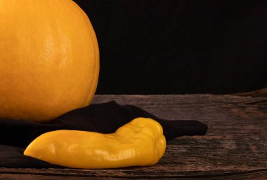 Ahşap bir masada sarı balkabağı ve uzun biber, yazı için yer.