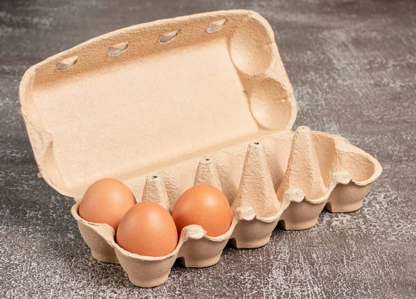 Fresh organic chicken eggs in open carton pack or egg container on brown background, set 3 of 12, stock photo