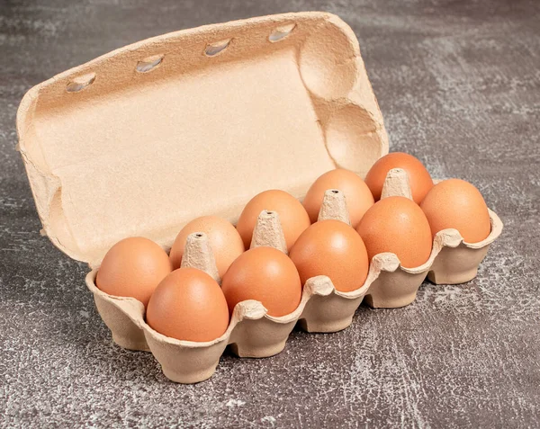 Fresh organic chicken eggs in open carton pack or egg container on brown background, set 11 of 12, stock photo
