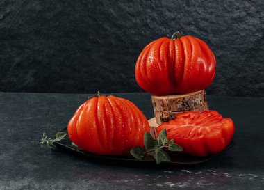 Tam ve dilimlenmiş taze Raf Coeur De Boeuf, kekikli sığır eti domatesleri.