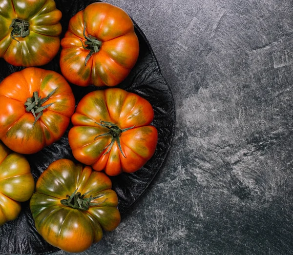 A group of Costoluto big tomatoes on a grey background, rustic concept, stock photo